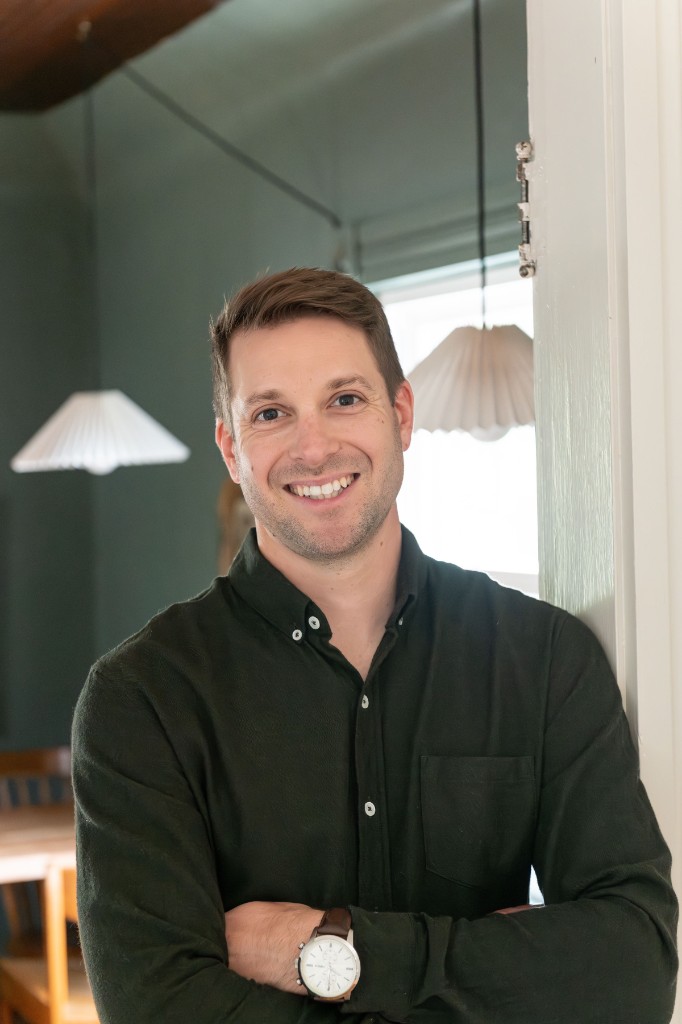 Jonathan Welzbacher, founder of Groundwork Security & Compliance, standing indoors in a green shirt